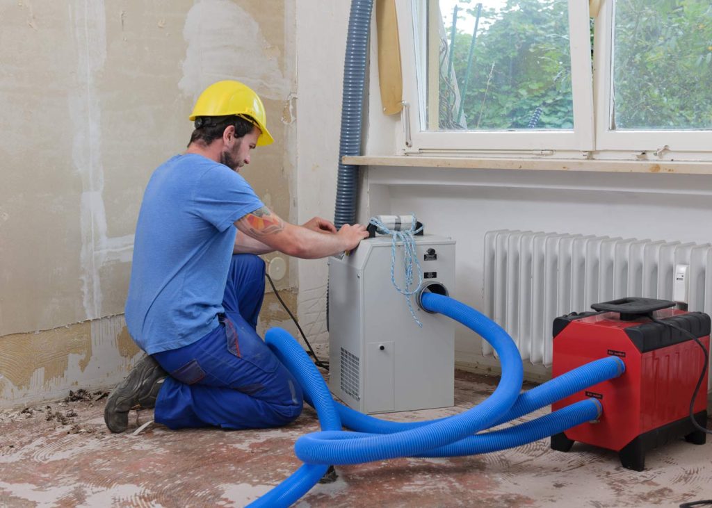 A worker setting up equipment for water damage restoration