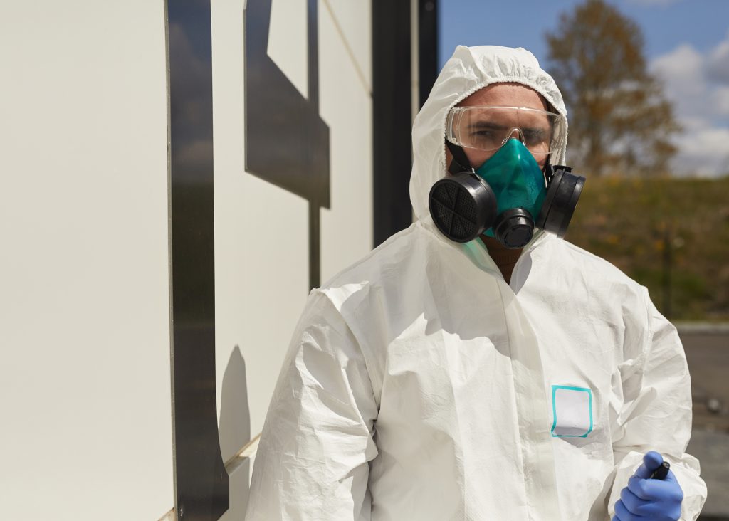 Technician in full safety gear and an air-purifying respirator