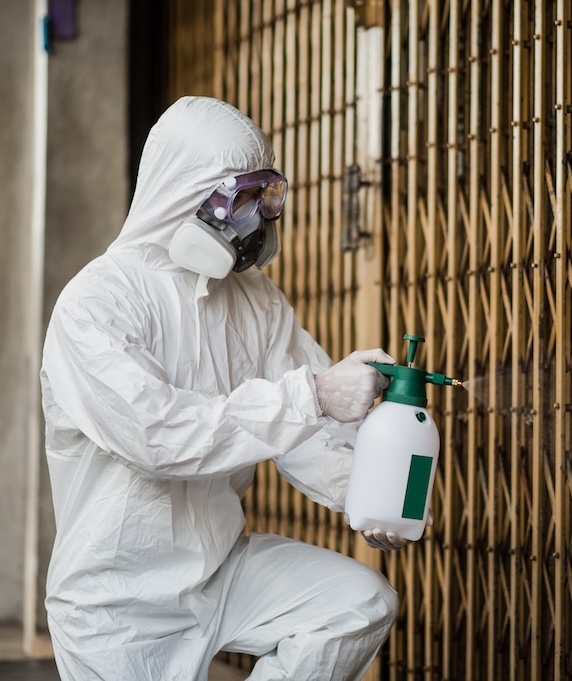 technician in PPE spraying down an area